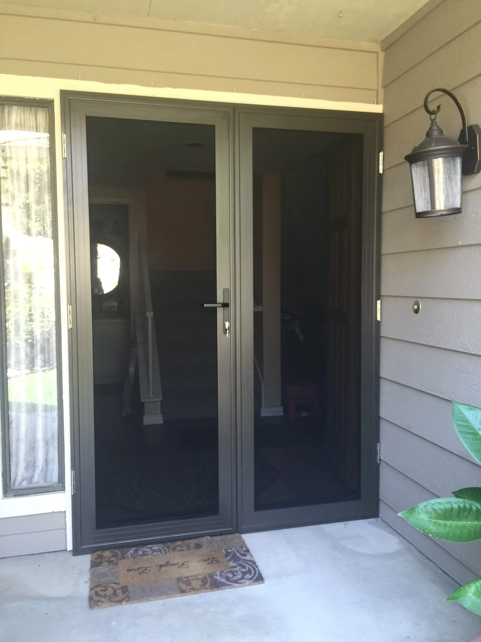 Bronze French-pair security screen doors installed on a covered porch